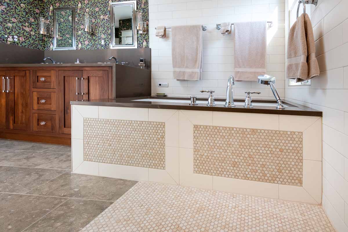 Eclectic bathroom featuring wooden cabinetry, patterned floral wallpaper, and white tiled walls with circular accents. 