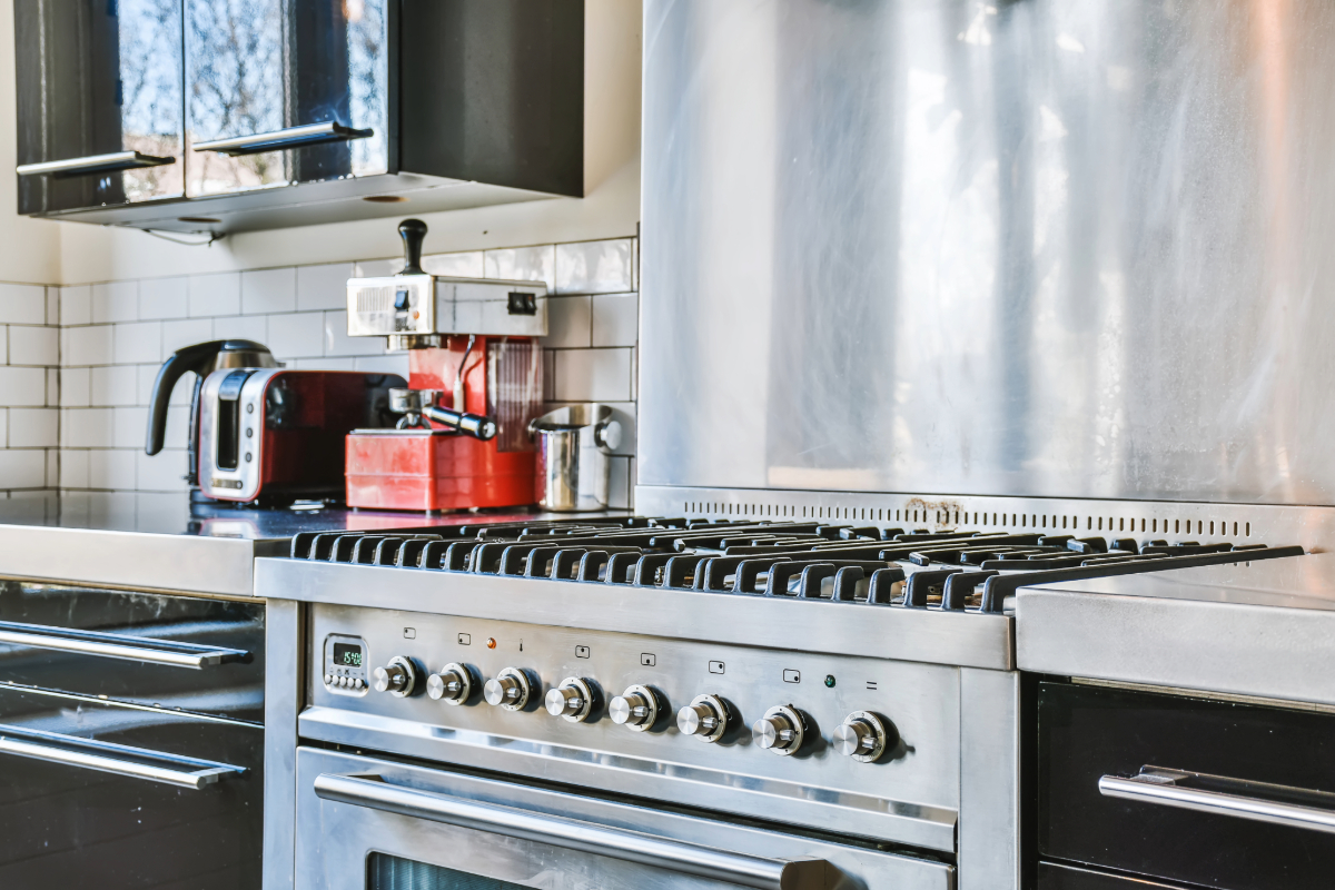 Modern kitchen with a stainless steel gas stove and hood, white subway tiles, and red kitchen appliances. 