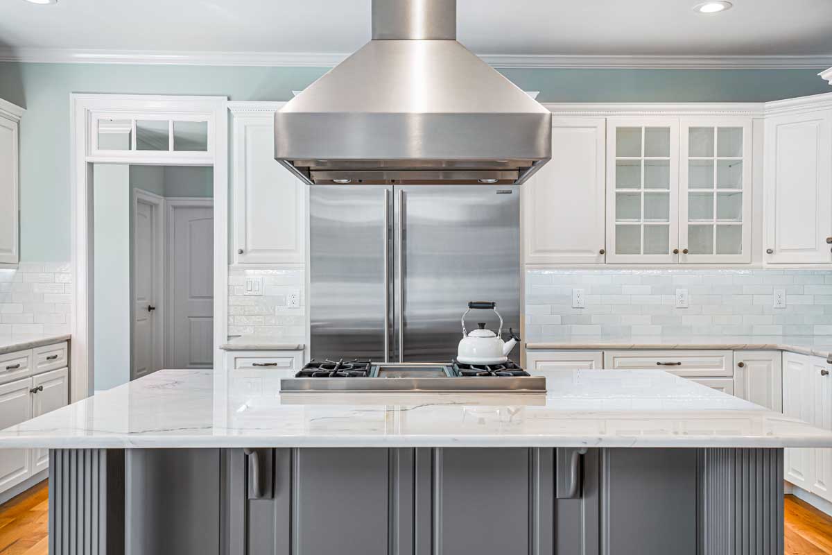 Spacious kitchen with white cabinetry, stainless steel stove and hood, and a light blue accent wall. 