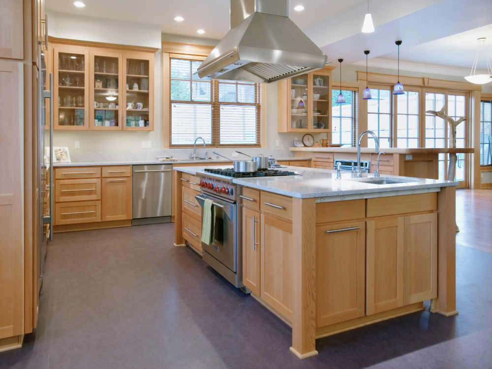 Modern kitchen remodel with light wood cabinetry and central island, featuring stainless steel appliances and granite countertops. 